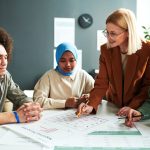 Confident teacher in eyeglasses explaining information in document